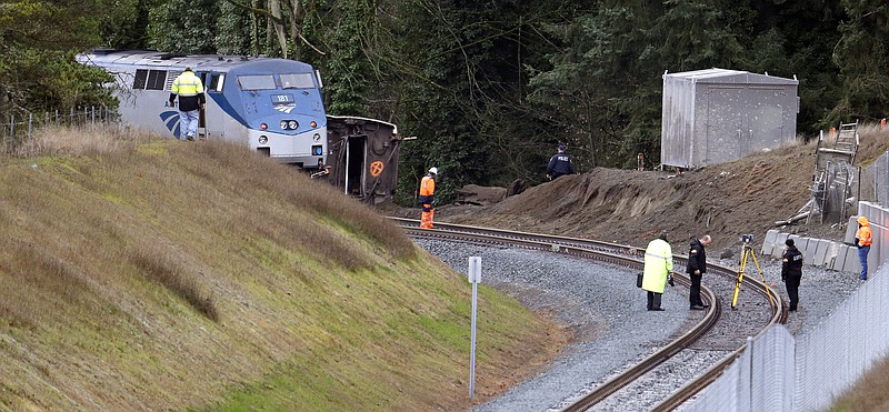 Cars from an Amtrak train remain on the tracks above where other cars spilled below onto Interstate 5 Monday, Dec. 18, 2017, in DuPont, Wash. The Amtrak train making the first-ever run along a faster new route hurtled off the overpass Monday near Tacoma and spilled some of its cars onto the highway below, killing some people, authorities said. Seventy-eight passengers and five crew members were aboard when the train moving at more than 80 mph derailed about 40 miles south of Seattle before 8 a.m., Amtrak said. (AP Photo/Elaine Thompson)

