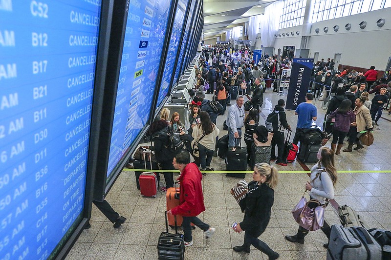 Travelers pass under the flight board showing cancellations in the North terminal on Monday Dec. 18, 2017 at Hartsfield-Jackson International Airport in Atlanta the day after a massive power outage brought operations to halt. Power was restored at the world's busiest airport after a massive outage Sunday afternoon that left planes and passengers stranded for hours, forced airlines to cancel more than 1,100 flights and created a logistical nightmare during the already-busy holiday travel season. (John Spink/Atlanta Journal-Constitution via AP)