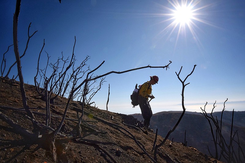 In this photo provided by the Santa Barbara County Fire Department, Santa Barbara County Fire Capt. Ryan Thomas hikes down steep terrain below East Camino Cielo to meet with his crew and root out and extinguish smoldering hot spots in Santa Barbara, Calif., Tuesday, Dec. 19, 2017. Officials estimate that the Thomas Fire will grow to become the biggest in California history before full containment, expected by Jan. 7, 2018. (Mike Eliason/Santa Barbara County Fire Department via AP)