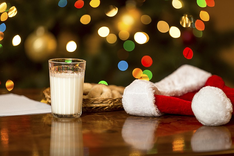 Closeup photo of glass of milk and cookies for Santa on table