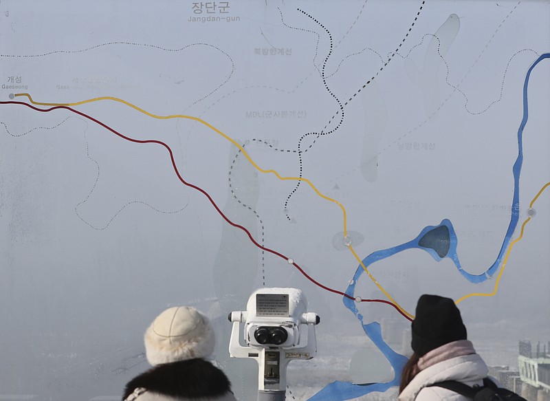 Visitors watch the north side through the glass showing a map of the border area between North and South Koreas at the Imjingak Pavilion in Paju, South Korea, Thursday, Dec. 21, 2017. South Korea's military fired 20 rounds of warning shots Thursday as North Korean soldiers approached a borderline after their comrade defected to South Korea, officials said. (AP Photo/Lee Jin-man)