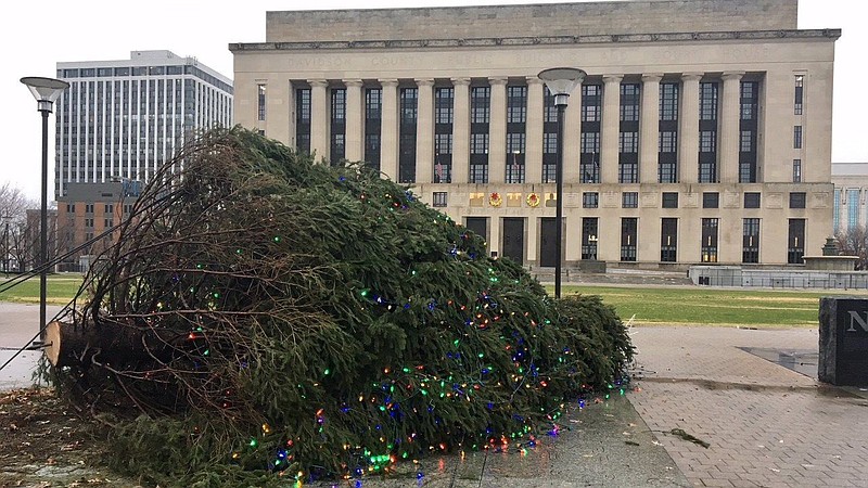 The Christmas tree in Nashville, Tenn.'s Public Square Park lies on its side on Saturday, Dec. 23, 2017. City officials say the culprit was a combination of wind, rain and possibly a defective anchor. A 35-foot tall Christmas tree still stands outside the state Capitol, which is not far from where this tree fell. (Kyle Cooke, Danielle Allen/WSMV via AP)