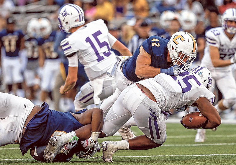 UTC defensive lineman Isaiah Mack, left, and UTC defensive lineman Hawk Schrider (42) tackle Furman running back Antonio Wilcox during the Mocs' home football game against the Furman Paladins at Finley Stadium on Saturday, Oct. 7, 2017, in Chattanooga, Tenn.