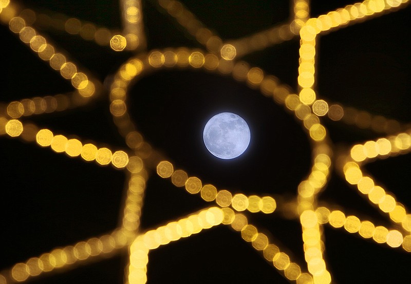 The moon is seen through Christmas decorations at the corner of Market Street and Third Street in downtown Chattanooga.