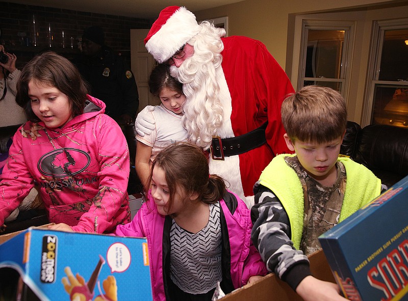 Madison Holland, 11, hugs Santa Claus as Hadley Holland, 11, Hanna Holland, 6, and Gage Holland, 8, look through boxes of presents as a part of the Santa Train Sunday, Dec. 24, 2017 at their home in Lookout Valley, Tenn. The Santa Train was established in 1965 by two Chattanooga Police officers to give families in need Christmas presents. 