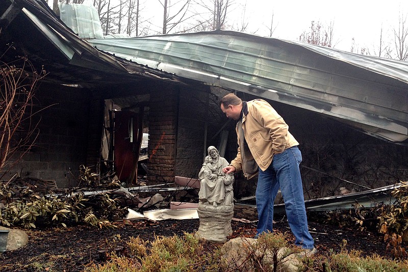 Senior Pastor Kim McCroskey inspects a statue outside the remains of the family life center at Roaring Fork Baptist Church in Gatlinburg on Dec. 6, 2016. The church and center burned down in fires a week earlier.