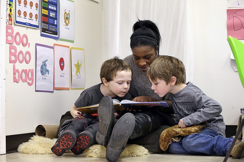 
              ** HOLD FOR SALLY HO STORY ** In this photo taken Feb. 12, 2016, assistant teacher D'onna Hartman, reads to Frederick Frenious, left, and Gus Saunders at the Creative Kids Learning Center, a school that focuses on pre-kindergarten for 4- and 5-year-olds, in Seattle. Hartman used the "boo boo bag" corner to settle the two down after a small altercation left one in tears. In perhaps an unexpected twist, historically conservative strongholds like Oklahoma and West Virginia are leading efforts to bring preschool to all and Alabama and Georgia are also red states that have notable programs. But some liberal leaning-cities like Seattle and New York also are running public pre-K programs. (AP Photo/Elaine Thompson, File)
            