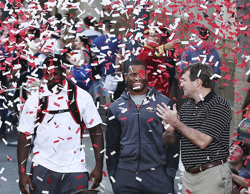 From left, Georgia linebacker Roquan Smith, running back Nick Chubb and coach Kirby Smart soak in the atmosphere as confetti rains down Wednesday afternoon during a Rose Bowl team function at Disneyland in Anaheim, Calif.