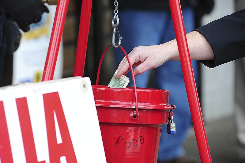 In this Nov. 22, 2017, file photo, a patron donates money in a Salvation Army red kettle in Wilkes-Barre, Pa. In this season of giving, charity seems to be getting an extra jolt because the popular tax deduction for charitable donations will lose a lot of its punch.  (Mark Moran/The Citizens' Voice via AP)