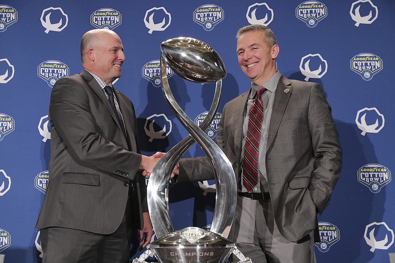 Southern California head coach Clay Helton, left, and Ohio State head coach Urban Meyer shake hands an pose for photos after a news conference for the Cotton Bowl NCAA college football game in Dallas, Thursday, Dec. 28, 2017. (AP Photo/LM Otero)