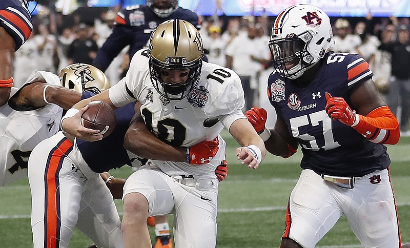 Central Florida quarterback McKenzie Milton (10) runs into the end zone for a touchdown against Auburn defensive back Javaris Davis, left, and Auburn linebacker Deshaun Davis (57) during the first half of the Peach Bowl NCAA college football game, Monday, Jan. 1, 2018, in Atlanta. (AP Photo/John Bazemore)