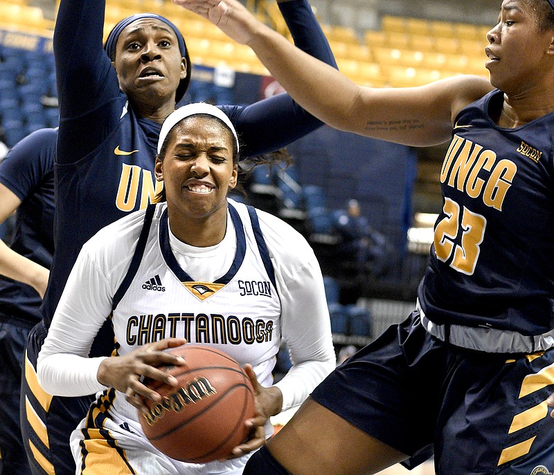 UTC's Arianne Whitaker (4) struggles between Greensboro's Ije Ajemba (25) and Te'ja Twitty (25).  The University of North Carolina Greensboro Trojans visited the University of Tennessee Chattanooga Mocs in Southern Conference women's basketball action at McKenzie Arena on January 4, 2018.