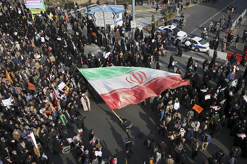 In this photo provided by Tasnim News Agency, a demonstrator waves a huge Iranian flag during a pro-government rally in the northeastern city of Mashhad, Iran, Thursday, Jan. 4, 2018. 