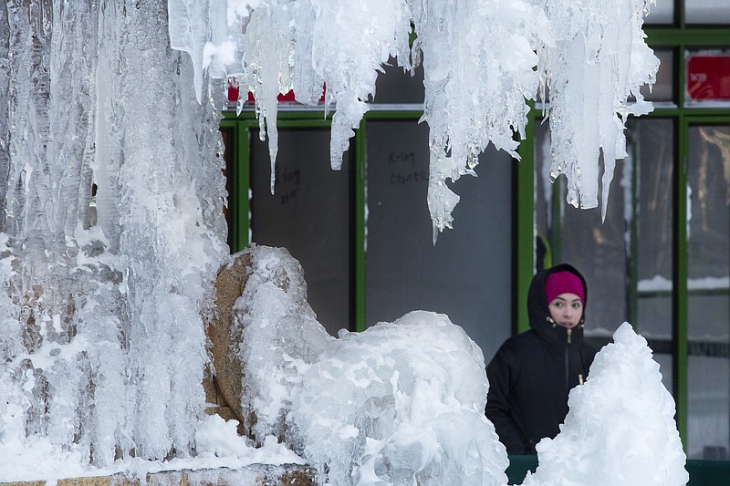 A woman passes an ice-covered fountain in New York's Bryant Park, Friday, Jan. 5, 2018. 