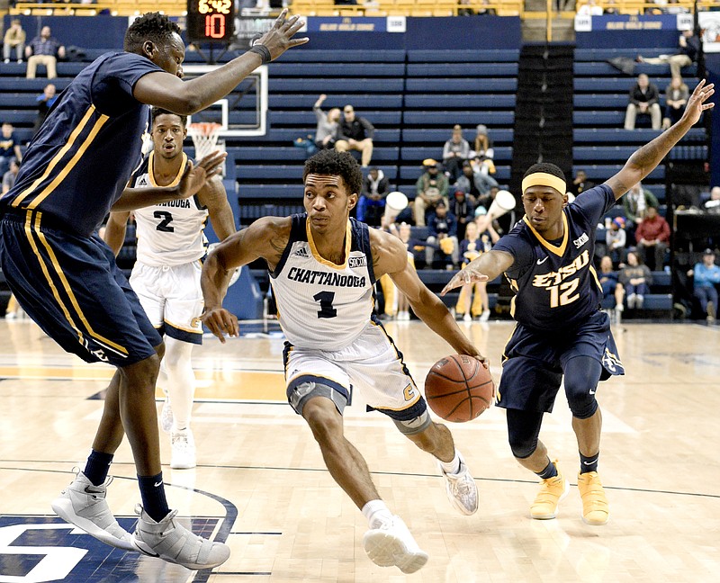 UTC's Rodney Chatman (1) drives to dribble past ETSU's Peter Jurkin (5) while Jurkin's teammate Jalan McCloud (12) reaches for the ball.  The East Tennessee State University Buccaneers visited the University of Tennessee Chattanooga Mocs in Southern Conference men's basketball action at McKenzie Arena on January 6, 2018.  