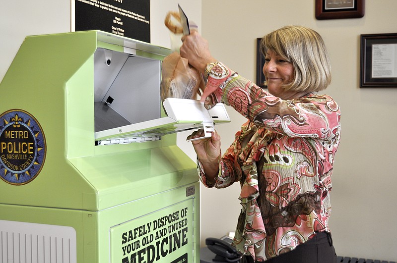 Lori Munkeboe, a Tennessee Department of Environment and Conservation employee, demonstrates how to properly dispose of unused medications in a collection box.