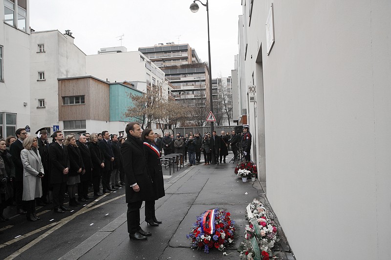 
              French President Emmanuel Macron, center and Paris mayor Anne Hidalgo observe a minute of silence outside the satirical newspaper Charlie Hebdo former office, to mark the third anniversary of the attack, in Paris, Sunday, Jan. 7, 2018. Macron paid respects to the 17 people killed when Islamic extremists attacked satirical newspaper Charlie Hebdo and a kosher supermarket three years ago, in the first of several attacks to rock France. (AP Photo/Christophe Ena, Pool)
            