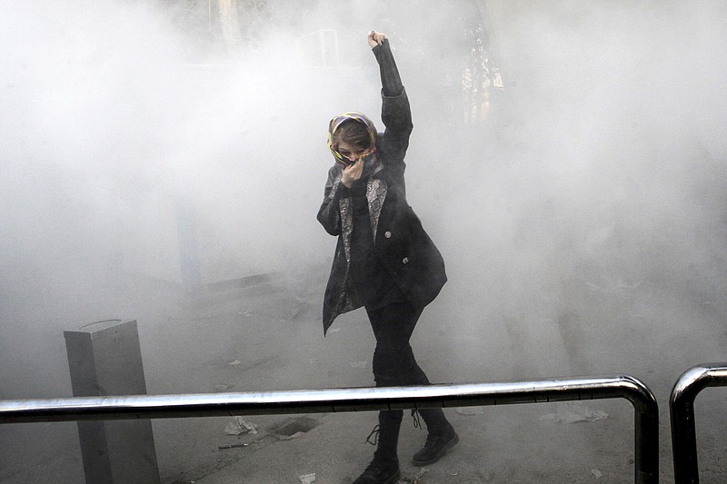 In this Dec. 30, 2017, photo made by an individual not employed by the Associated Press and obtained by the AP outside Iran, a university student attends a protest inside Tehran University while a smoke grenade is thrown by Iranian police, in Tehran, Iran. New unrest in Iran over the past 10 days appears to be waning, but anger over the economy persists. The protests in dozens of towns and cities also showed that a sector of the public was willing to openly call for the removal of Iran's system of rule by clerics -- frustrated not just by the economy but also by concern over Iran's foreign wars and general direction. (AP Photo, File)