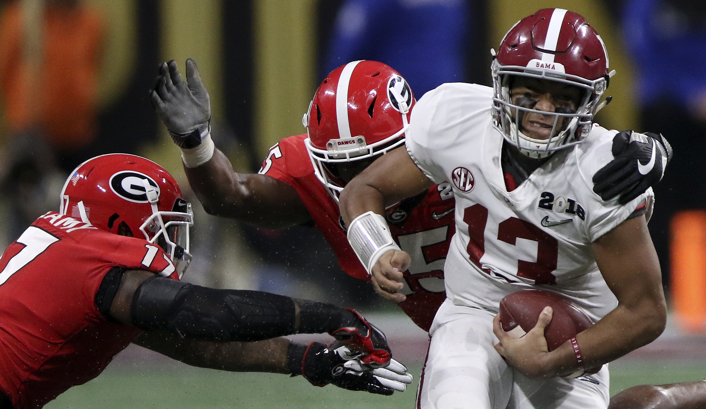 Alabama quarterback Tua Tagovailoa (13) evades Georgia linebackers Davin Bellamy (17) and D'Andre Walker (15) as he scrambles for a 9-yard gain during the College Football Playoff national championship at Mercedes-Benz Stadium on Monday, Jan. 8, 2018 in Atlanta, Ga.