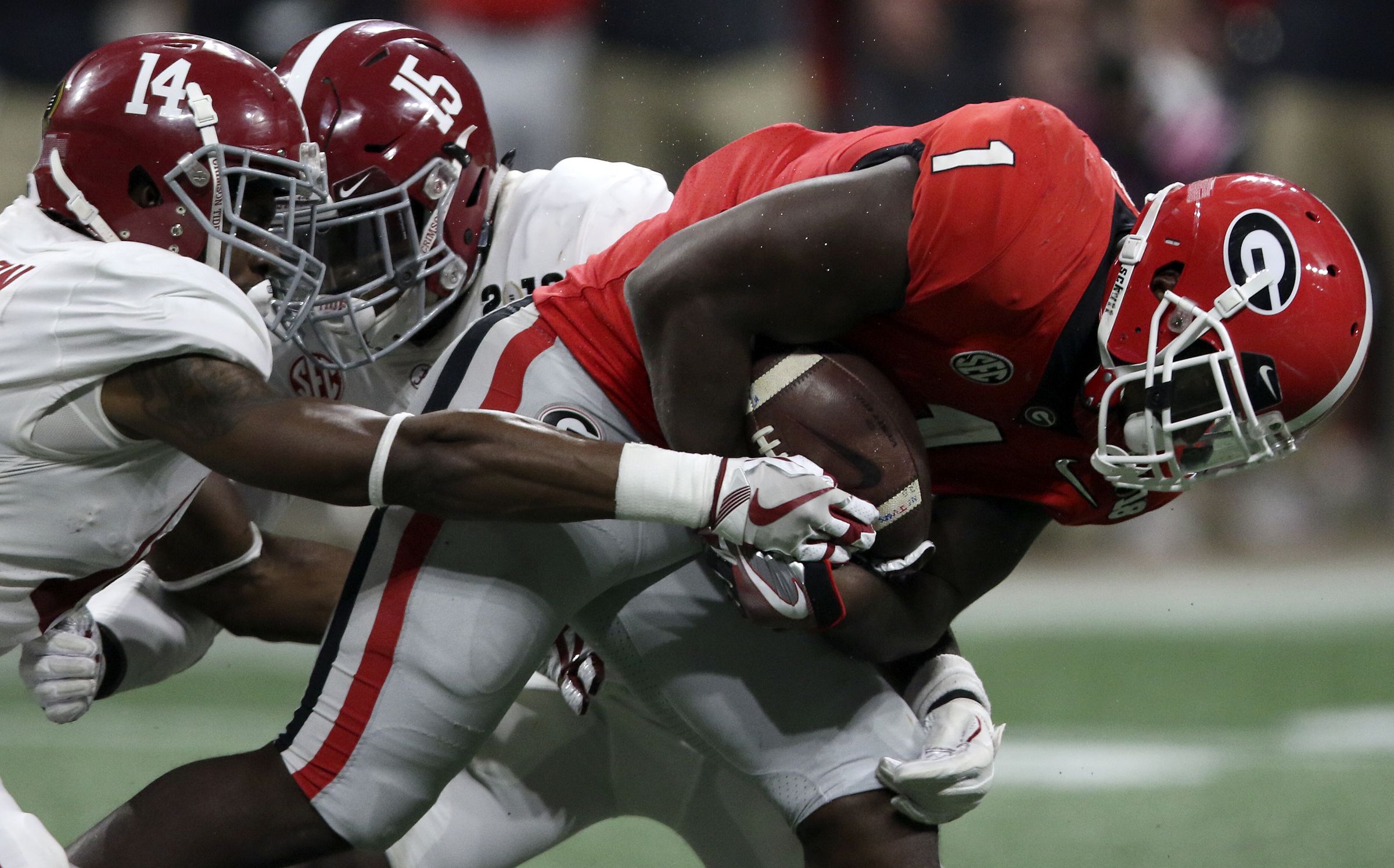 Georgia running back Sony Michel (1) fights through a tackle attempt by Alabama defensive back Deionte Thompson (14) for a 13-yard gain during the College Football Playoff national championship at Mercedes-Benz Stadium on Monday, Jan. 8, 2018 in Atlanta, Ga. He would be brought down by Alabama defensive back Ronnie Harrison (15).