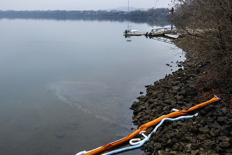 Oil flows from Citico Creek around the edges of protective booms into the Tennessee River after a spill on Tuesday, Jan. 9, 2018, in Chattanooga, Tenn. An unknown amount of oil flowed into the river before the spill was contained, according to Chattanooga Fire Department spokesperson Bruce Garner, and firefighters as well as environmental organizations are working to contain the spill and determine its origin.