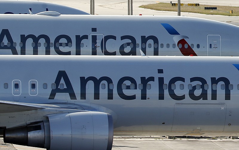 FILE - In this Monday, Nov. 6, 2017, file photo, a pair of American Airlines jets are parked on the airport apron at Miami International Airport in Miami. Dozens of companies have announced they are giving their employees bonuses, following the passage of the Republican tax plan that President Donald Trump signed into law in December. American Airlines is handing out $1,000 bonuses to its employees. (AP Photo/Wilfredo Lee, File)