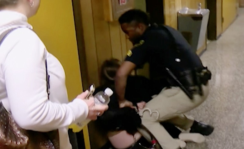 In this Monday, Jan. 8, 2018, image made from a video provided by KATC-TV middle-school English teacher Deyshia Hargrave is handcuffed by a city marshal after complying with a marshal's orders to leave a Vermilion Parish School Board meeting in Abbeville, La., west of New Orleans. Hargrave was removed from the school board meeting, forcibly handcuffed and jailed after questioning pay policies during a public comment period. (KATC-TV via AP)