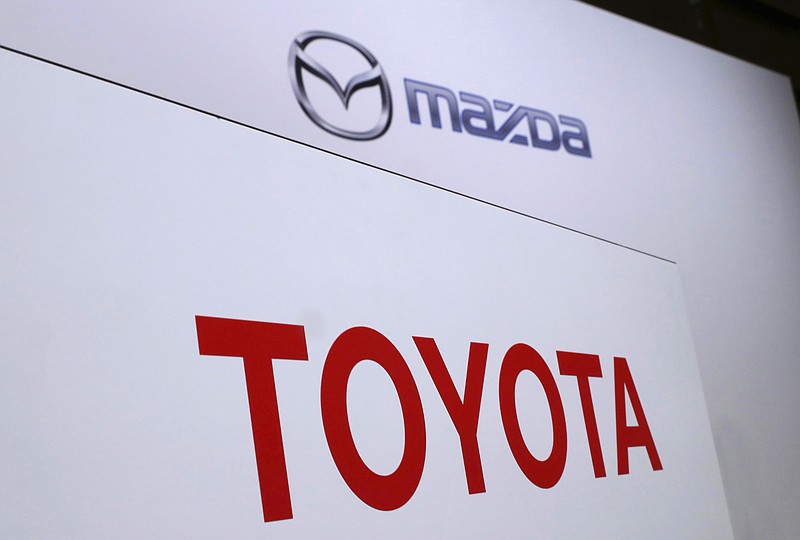 FILE- In this Aug. 4, 2017, file photo, logos of Toyota Motor Corp., bottom, and Mazda Motor Corp., top, are placed prior to a news conference in Tokyo.