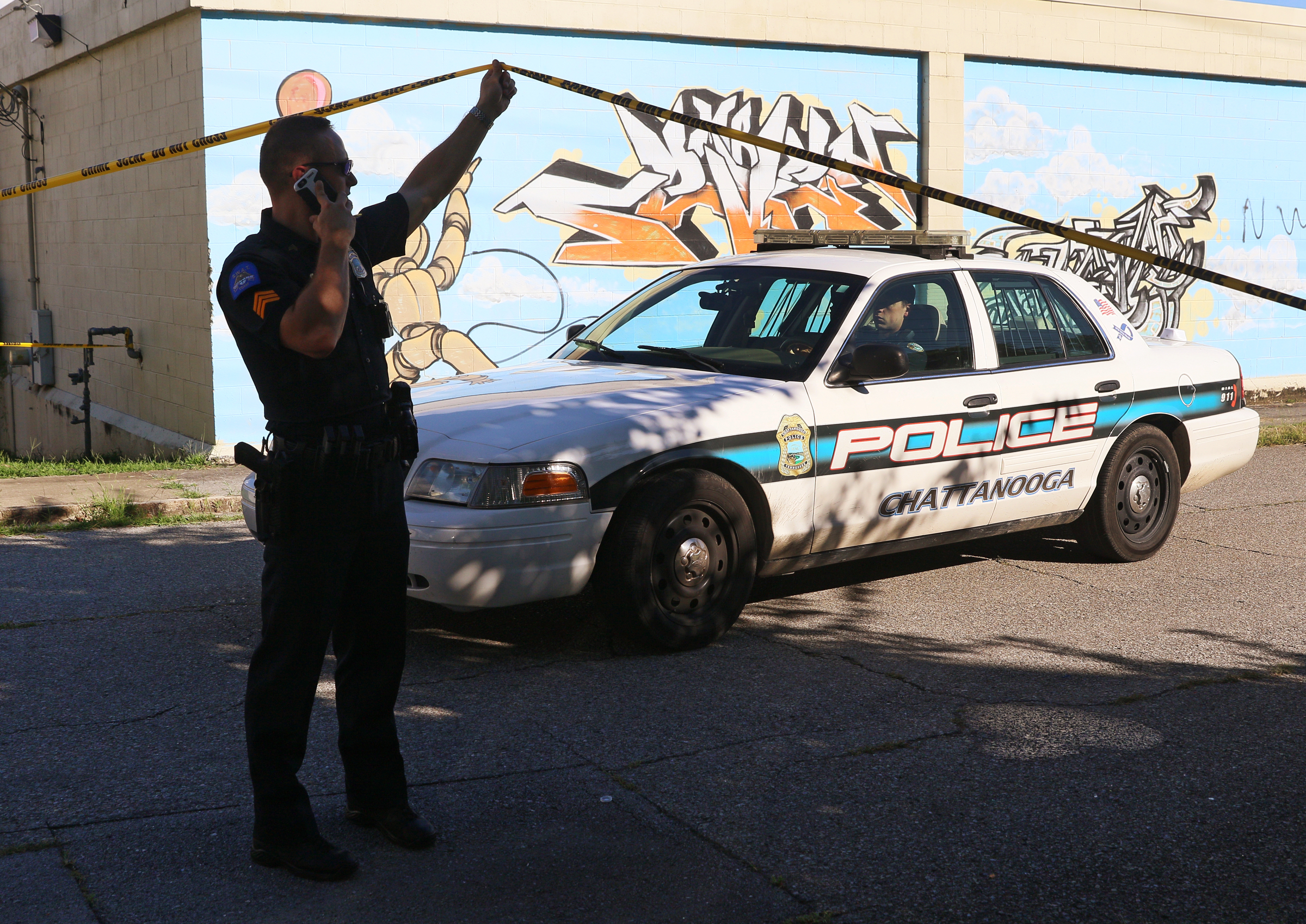 A Chattanooga Police Officer raises crime scene tape for another officer to leave the scene Wednesday, Aug. 16, 2017, at a crime scene on Oakland Avenue at 43rd Street in Chattanooga, Tenn. A man was shot in the 4300 block of Oakland Avenue and sustained injuries that were not life-threatening.