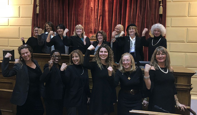 Rhode Island lawmakers wearing black to in solidarity with the Time's Up movement and as a statement against sexual misconduct stand at the House speaker's rostrum at the Statehouse in Providence, R.I., on Tuesday, Jan. 9., 2018. (AP Photo/Jennifer McDermott)