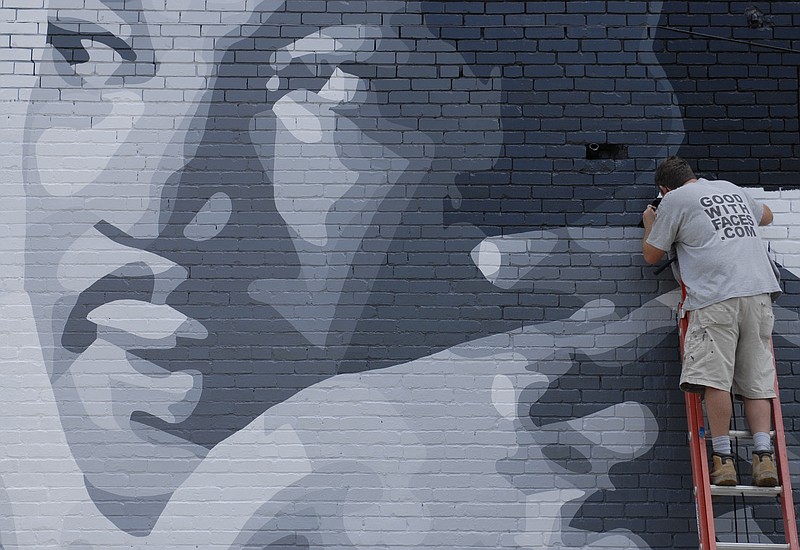 Artist Kevin Bate works on a mural of Martin Luther King Jr. at Blue Boy Barber Shop on MLK Boulevard in 2012.