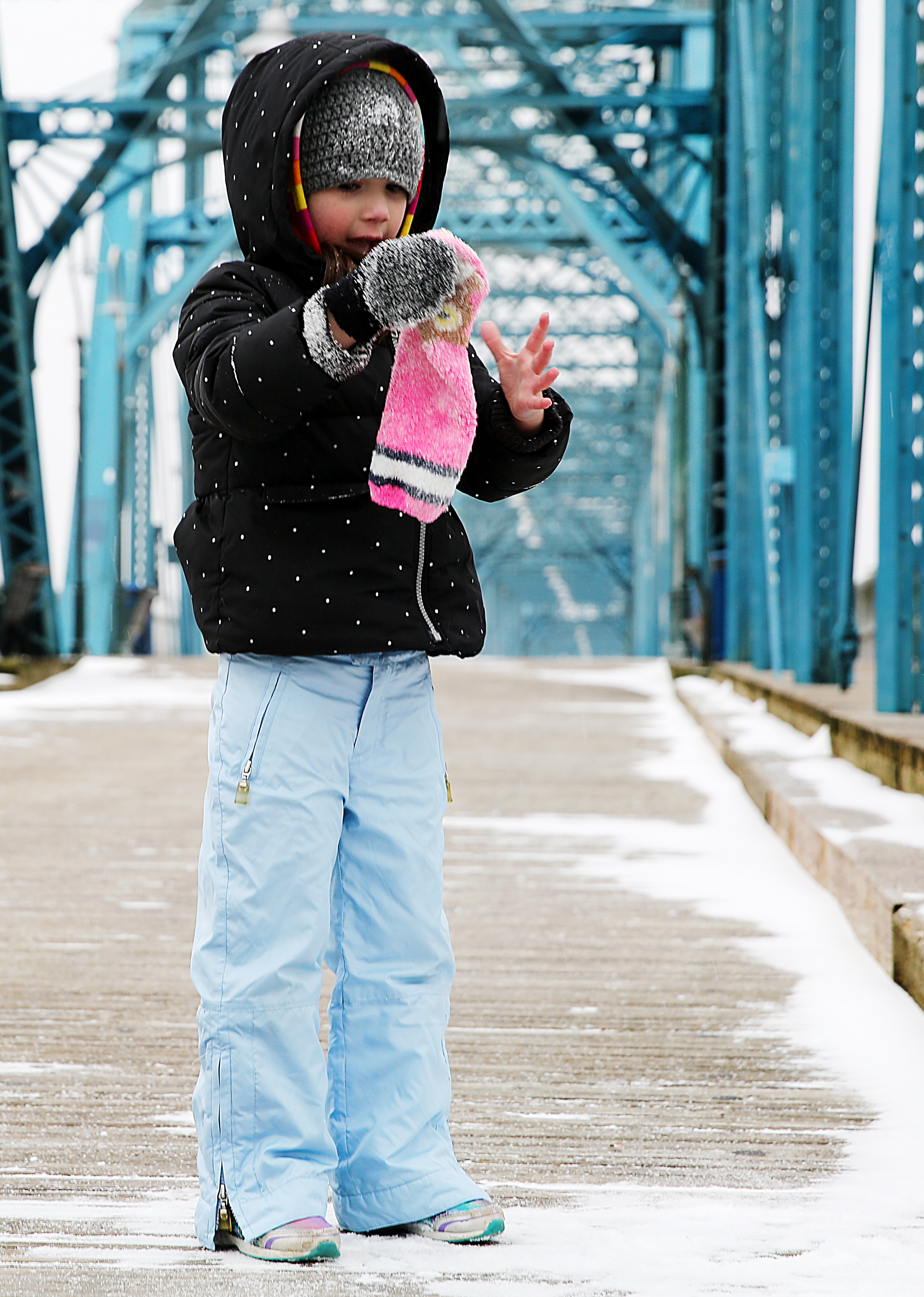 Ava Zani, 4, cleans the snow off of a sock she is using as a glove while playing on Walnut Street Bridge Tuesday, Jan. 16, 2018 in Chattanooga, Tenn. A light snow covered areas of Chattanooga Tuesday evening causing many schools and businesses to close for precautionary reasons.