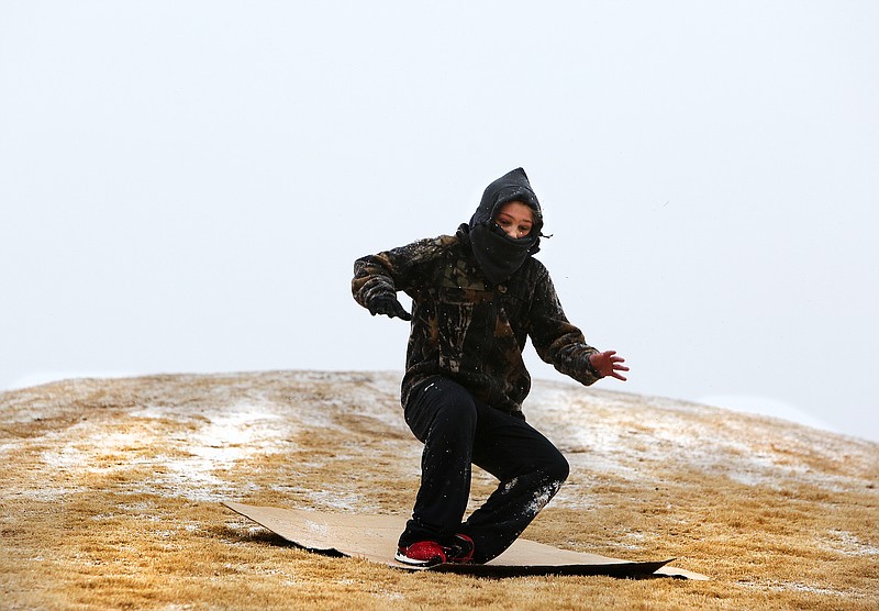 Will Reason, 10, jumps up to get extra propulsion as he slides down a hill in Renaissance Park on a cardboard box Tuesday, Jan. 16, 2018 in Chattanooga, Tenn. Reason and his family moved to a condo beside Renaissance Park less than a week ago and decided to take advantage of the light snow the Chattanooga received Tuesday evening. 