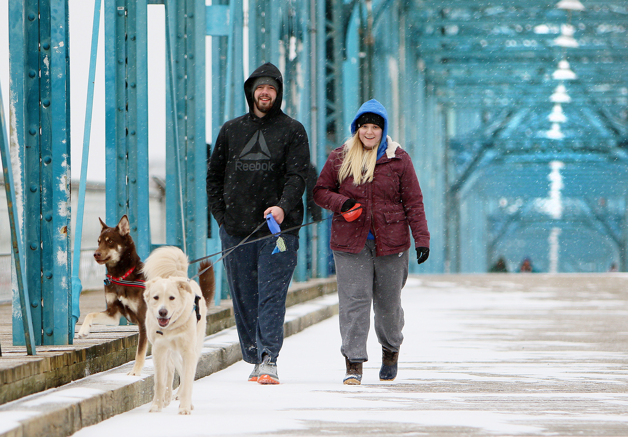 Quentin Slade walks Olli as Kelsey Batts walks Maverik  Tuesday, Jan. 16, 2018 on the Walnut Street Bridge in Chattanooga, Tenn. Chattanooga received a light snow Tuesday evening causing many businesses and schools to close for precautionary reasons.