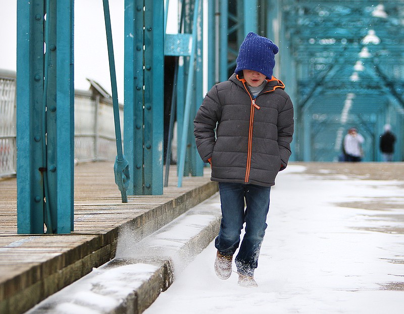 Cason O'Connor, 8, kicks up snow as he walks on Walnut Street Bridge Tuesday, Jan. 16, 2018 in Chattanooga, Tenn. Cason and his family decided to venture out of their house Tuesday evening when they saw the snow had begun to accumulate. 