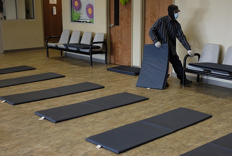 In this Jan. 7, 2015, staff file photo, volunteer Anthony Wayne sets up mats as they set up an overnight shelter at the Chattanooga Community Kitchen in Chattanooga, Tenn., in preparation for single-digit temperatures overnight.