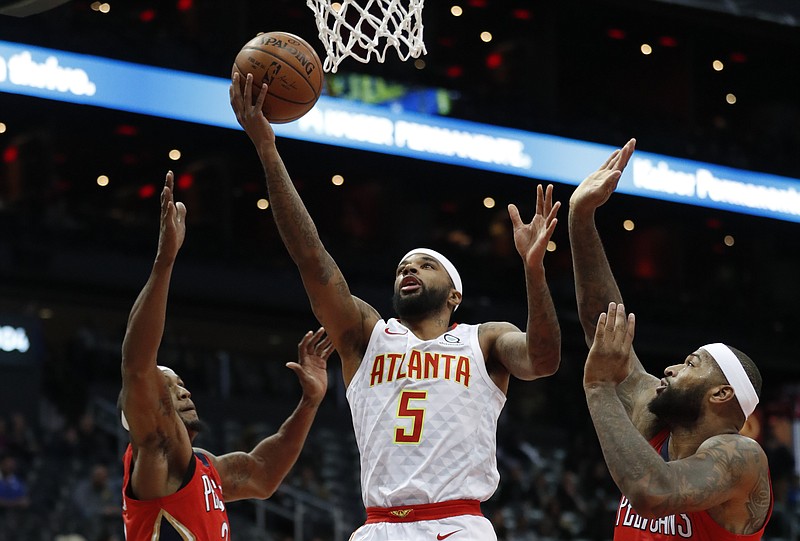 Atlanta Hawks guard Malcolm Delaney (5) goes between New Orleans Pelicans' Dante Cunningham (33) and DeMarcus Cousins (0) as he goes in for a shot during the first half of an NBA basketball game Wednesday, Jan. 17, 2018, in Atlanta. (AP Photo/John Bazemore)