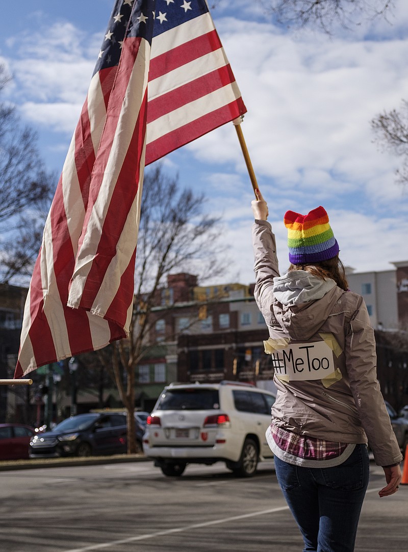 Lillian Kight holds an American flag with the #MeToo hashtag on her back as she marches with other demonstrators along 4th Street during the Chattanooga Women's March on Saturday, Jan. 20, 2018, in Chattanooga, Tenn. Thousands of demonstrators gathered at Coolidge Park and marched across the Market Street Bridge through the city's tourist district to show solidarity with a national women's rights movement.
