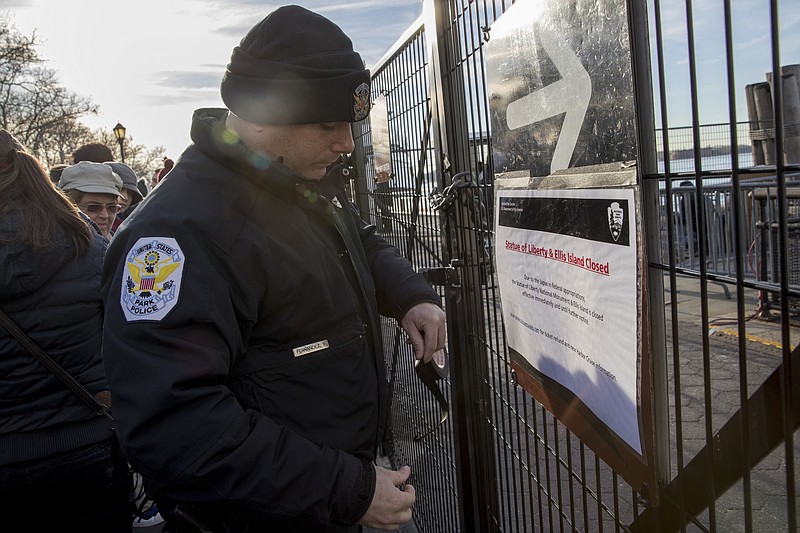 A United States Park Police officer post a sign informing of the Statue of Liberty and Ellis Island closing at an entrance to the ferry, Saturday, Jan. 20, 2018, in New York. 