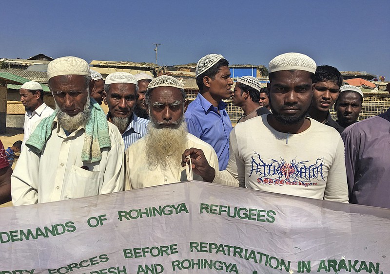 In this Jan. 20, 2018, photo, a group of Rohingya refugees hold banner that show a list of demand before Bangladesh and Myanmar governments start the process of repatriation, at Kutupalong refugee camp, near Cox's Bazar, Bangladesh. With the first repatriations of Rohingya refugees back to Myanmar just days away, and more than 1 million living in refugee camps in Bangladesh, international aid workers, local officials and the refugees say preparations have barely begun and most refugees would rather contend with the squalor of the camps than the dangers they could face if they return home. It's unclear if more than a handful of Rohingya will even be willing to go home. (AP Photo/Rishabh R. Jain)