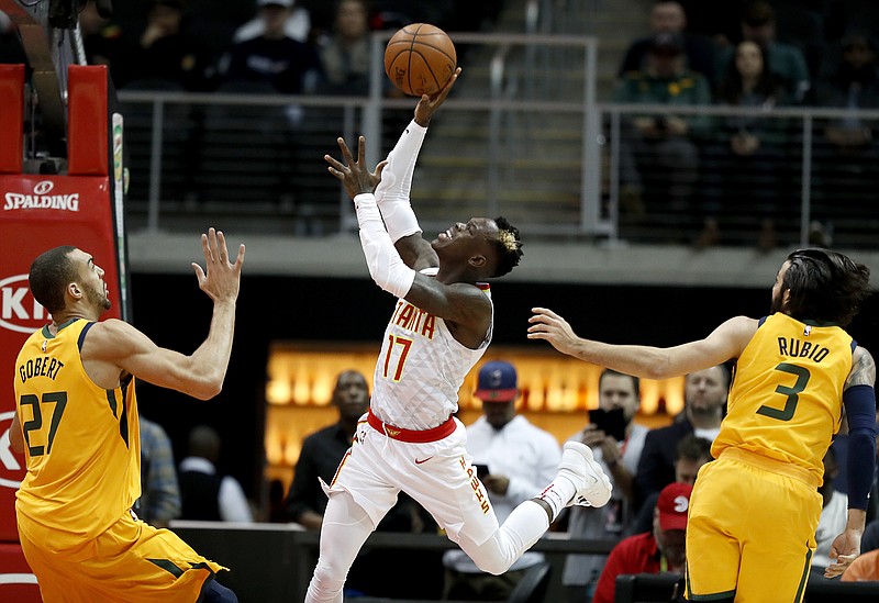 Atlanta Hawks' Dennis Schroder, center, of Germany, puts up a shot against the defense of Utah Jazz's Rudy Gobert (27), of France, and Ricky Rubio, of Spain, in the first quarter of an NBA basketball game in Atlanta, Monday, Jan. 22, 2018. Atlanta won 104-90. (AP Photo/David Goldman)