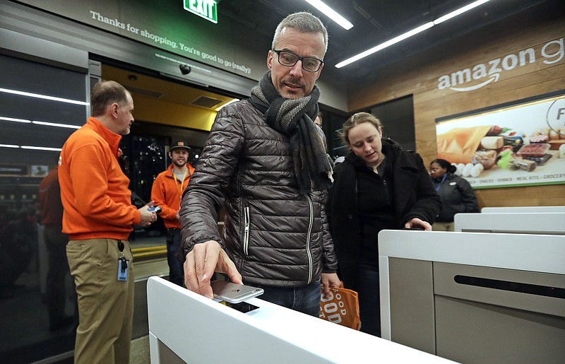 A customer scans his Amazon Go cellphone app at the entrance as he heads into an Amazon Go store, Monday, Jan. 22, 2018, in Seattle. The store, which opened to the public on Monday, allows shoppers to scan their smartphone with the Amazon Go app at a turnstile, pick out the items they want and leave. The online retail giant can tell what people have purchased and automatically charges their Amazon account. (AP Photo/Elaine Thompson)