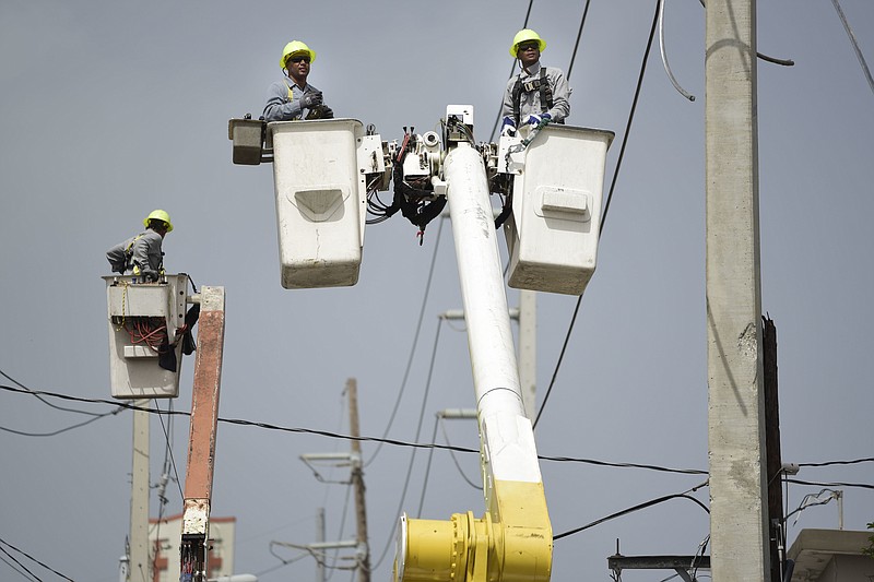 FILE - In this Oct. 19, 2017 file photo, a brigade from the Electric Power Authority repairs distribution lines damaged by Hurricane Maria in the Cantera community of San Juan, Puerto Rico. The announcement that Puerto Rico’s governor is moving to privatize the U.S. territory’s public power company has many on the island of 3.3 million people asking whether this will finally bring them more affordable electric bills and more reliable service.  (AP Photo/Carlos Giusti, File)
