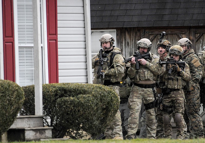 As the search continues just before sundown Tuesday, members of the Marion County Special Response Team stand ready outside a house on Ketner Street in Powell's Crossroads.