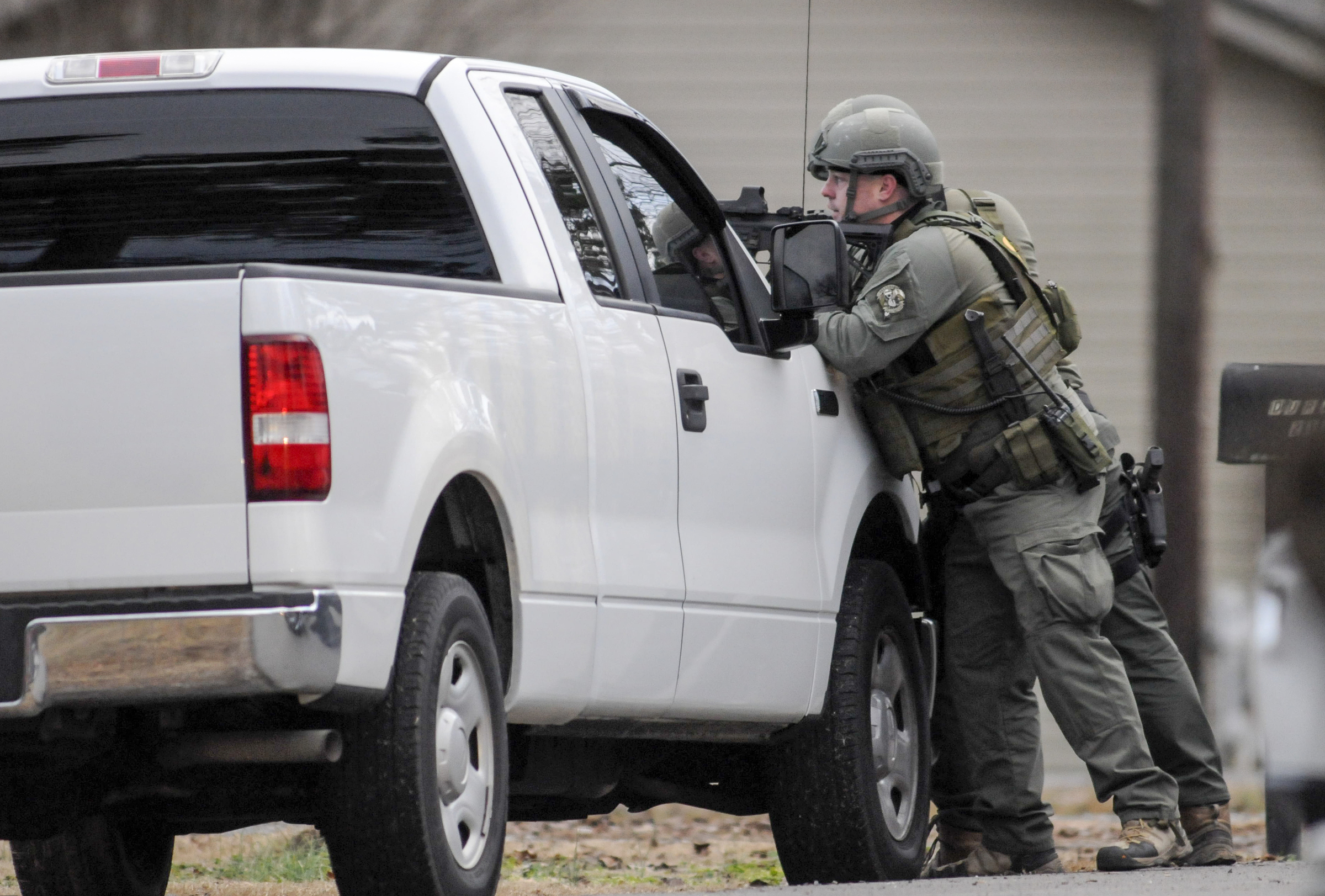 Members of the Marion County Special Response Team stand ready outside a house on Ketner Street in Powell's Crossroads just before sundown Tuesday.