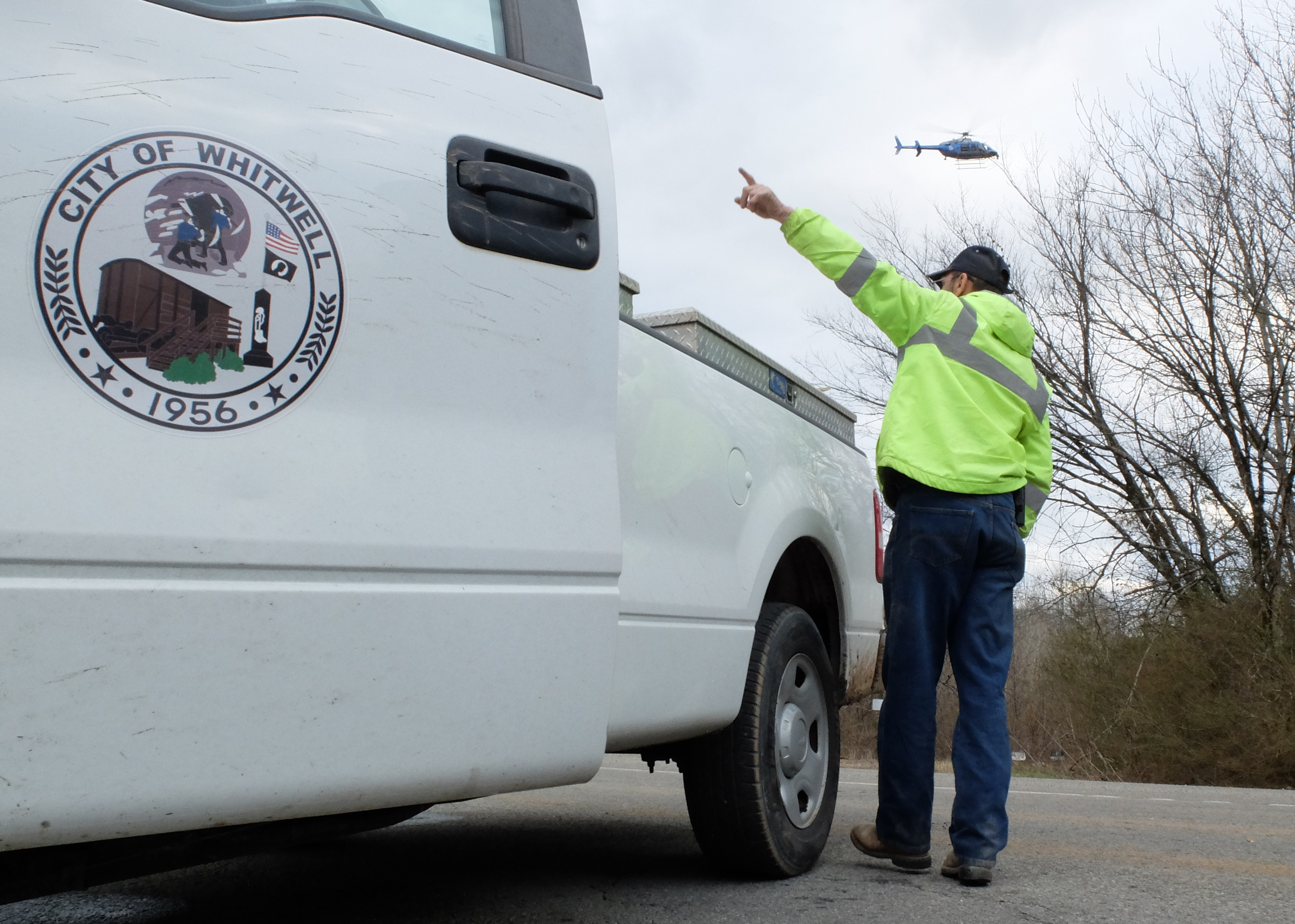City of Whitwell employee directs traffic onto S. Magnolia Street from State Highway 283 as a Georgia State Patrol helicopter hovers during Tuesday's manhunt near Whitwell.