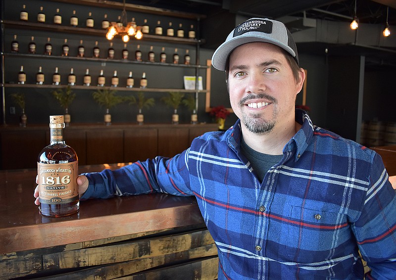 Tim Piersant, owner and co-founder of Tennessee Stillhouse, sits with a bottle of Native whiskey at the company's new distillery on Riverfront Parkway. Bottles are for sale at the micro-distillery on Market Street and in some local liquor stores.