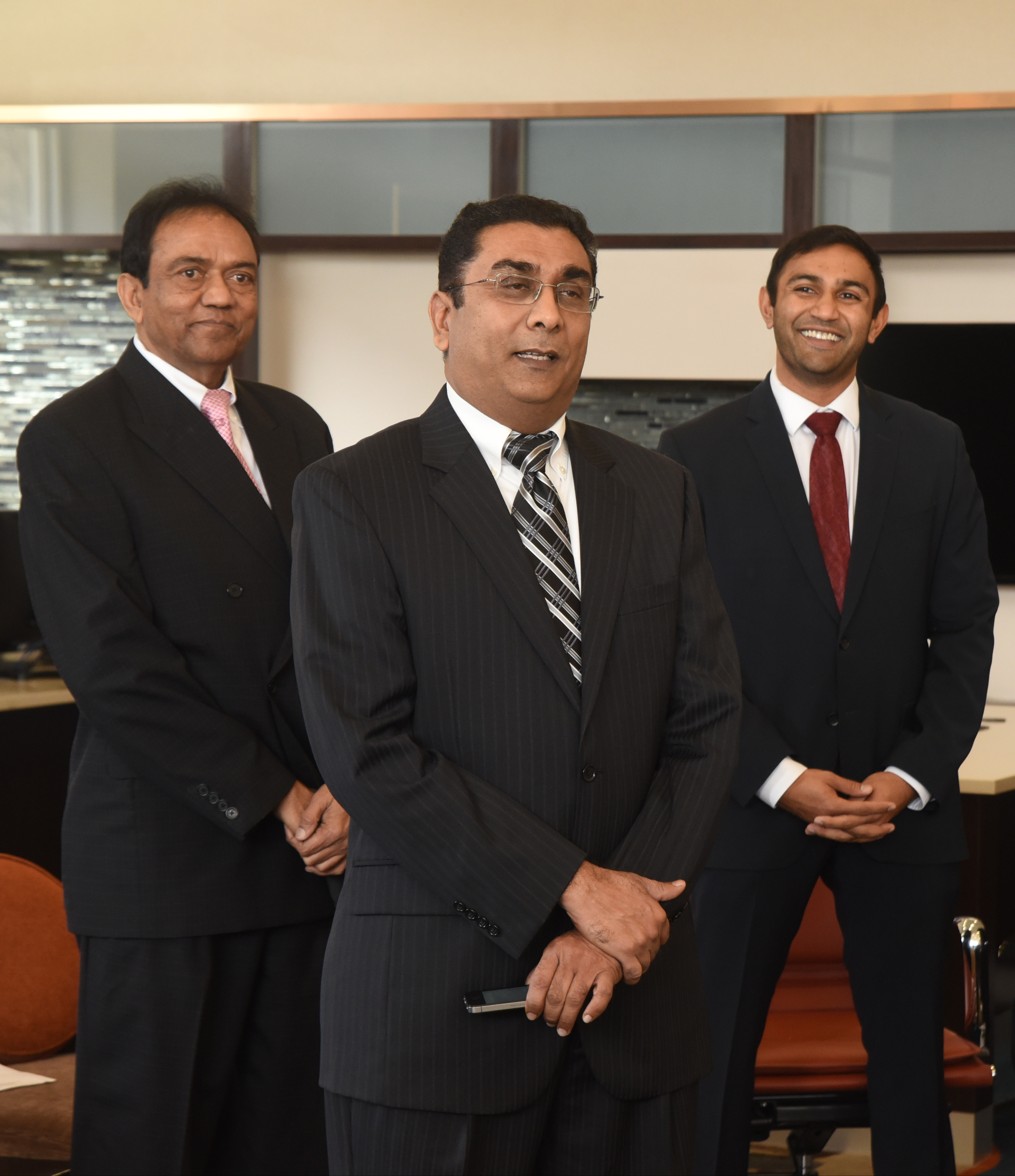 Charles Amin, Bob Bhagat and Roshan Amin, from left, participate Wednesday, December 16, 2015 in the grand opening of Holiday Inn & Suites .
