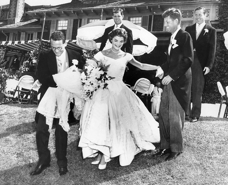 Jacqueline Bouvier Kennedy, is escorted by her groom, Sen. John F. Kennedy and Charles Bartlett down the hill at Hammersmith Farm at their wedding reception in 1953 in Rhode Island. Others looking on are Edward Kennedy and Torbert MacDonald.