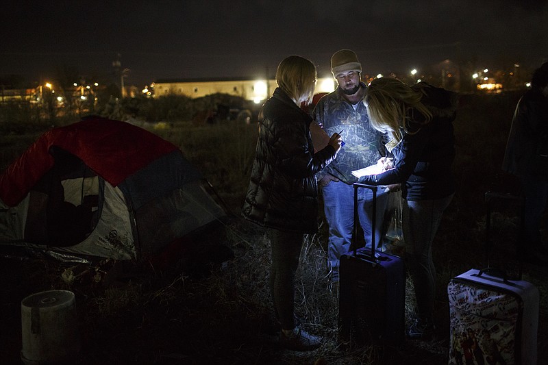 Theresa Biggs, right, and Tammie Carpenter, left, ask Josh Lillard questions at a homeless camp during an annual Point in Time Homeless Count on Thursday, Jan. 25, 2018, in Chattanooga, Tenn. Volunteers conducted surveys of homeless individuals and families in the region to provide data that will help service providers to offer targeted care and outreach.